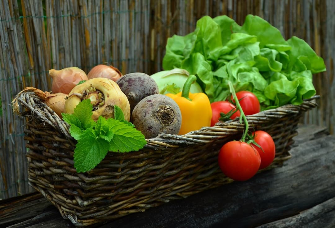 Wicker basket filled with fresh vegetables on a wooden surface
