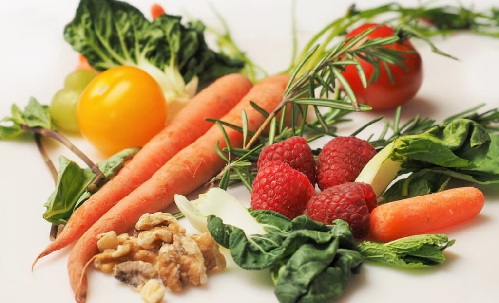 Assorted fresh vegetables and berries arranged on a white background