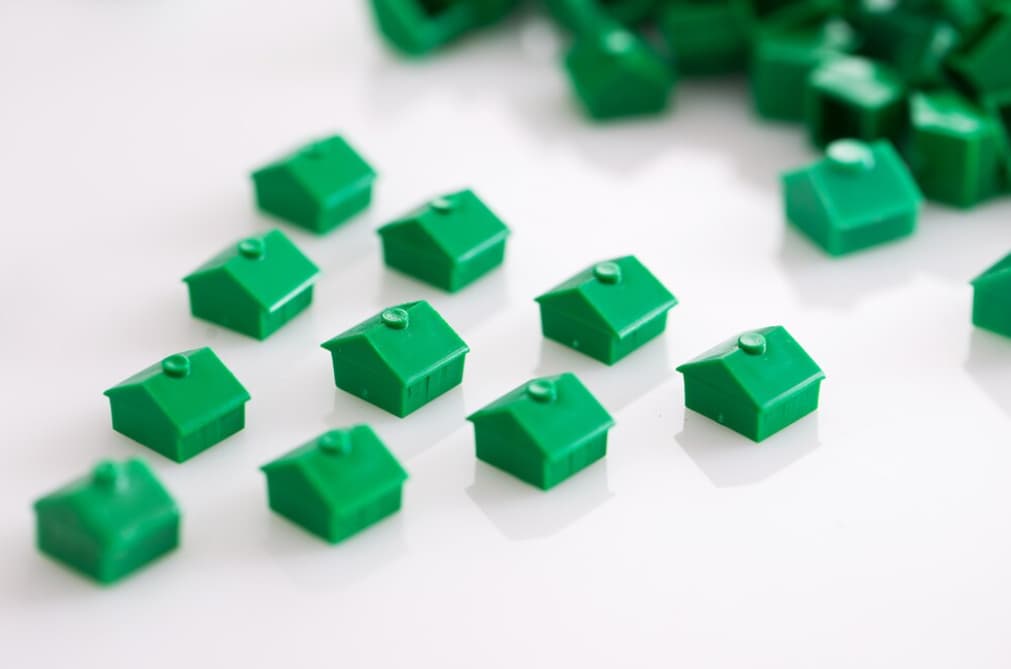 A collection of miniature green houses scattered on a white surface